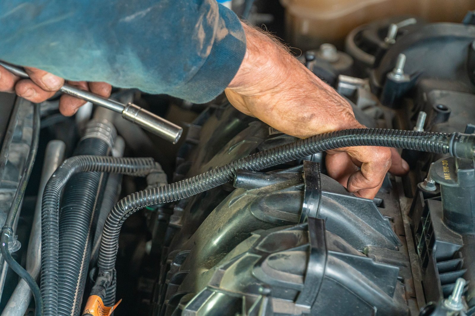 Hands using a tool to work on an engine