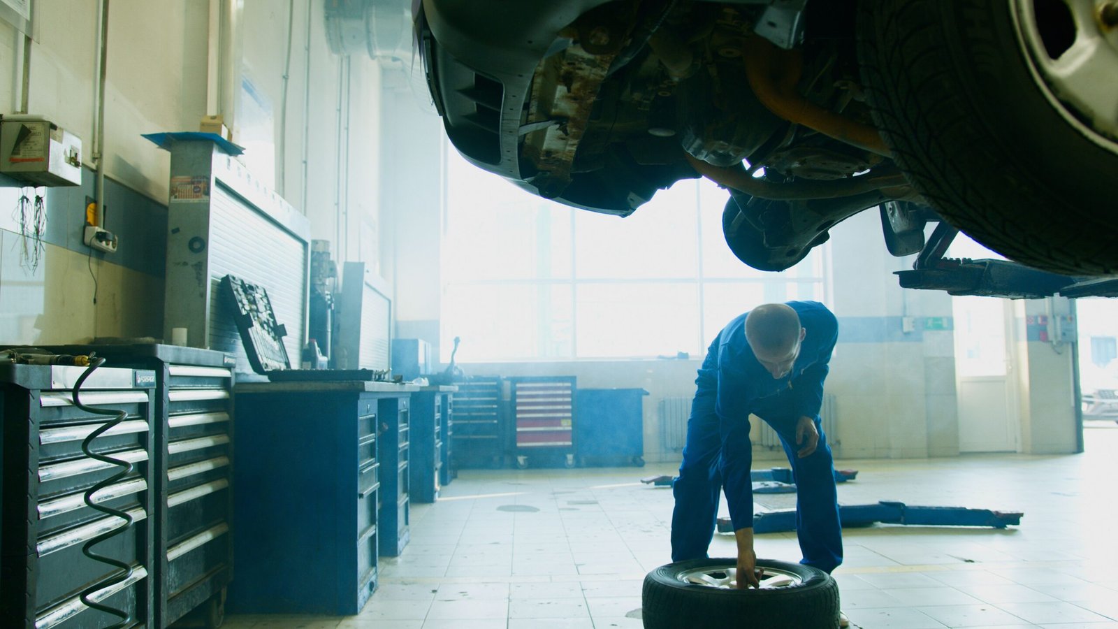Mechanic working in a garage beneath a raised car